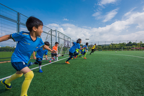 开学上学校踢球,春天到了小朋友们在草地上踢足球